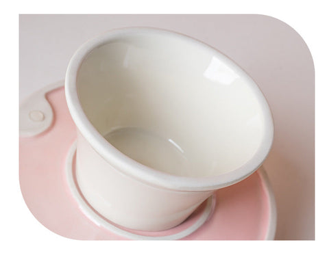 White ceramic cat bowl viewed from above on a pink silicone mat.